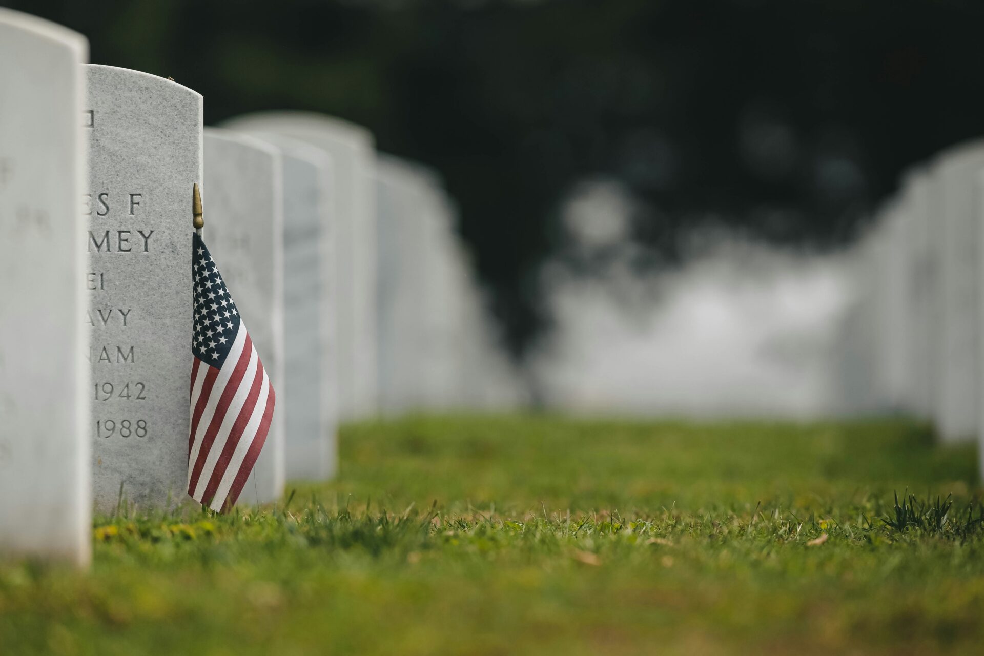 American flag next to service member's grave marker in honor of Memorial Day